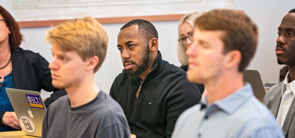 Students in classroom setting listen to presentation