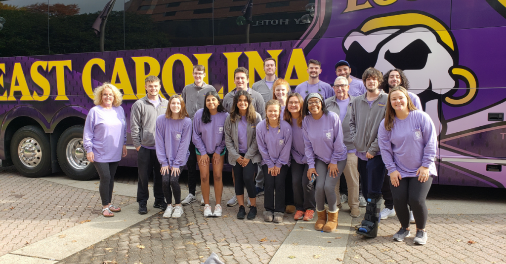 RMI Students stand outside of ECU bus painted with ECU's mascot