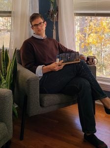 Dr. Erik Taylor reads a book next to an open window