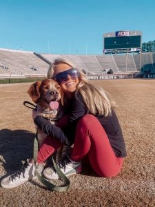Photo of Kristen Butts with her canine companion on ECU's Dowdy-Ficklen Stadium
