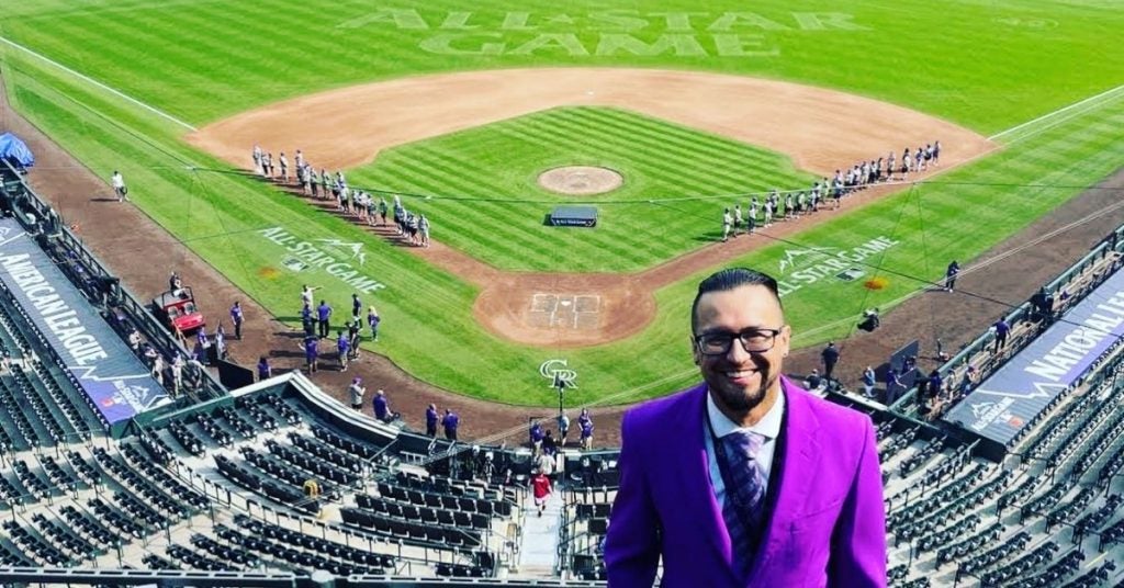 SHL Alumni, clad in purple suit, stands with the MLB All-Star field behind him