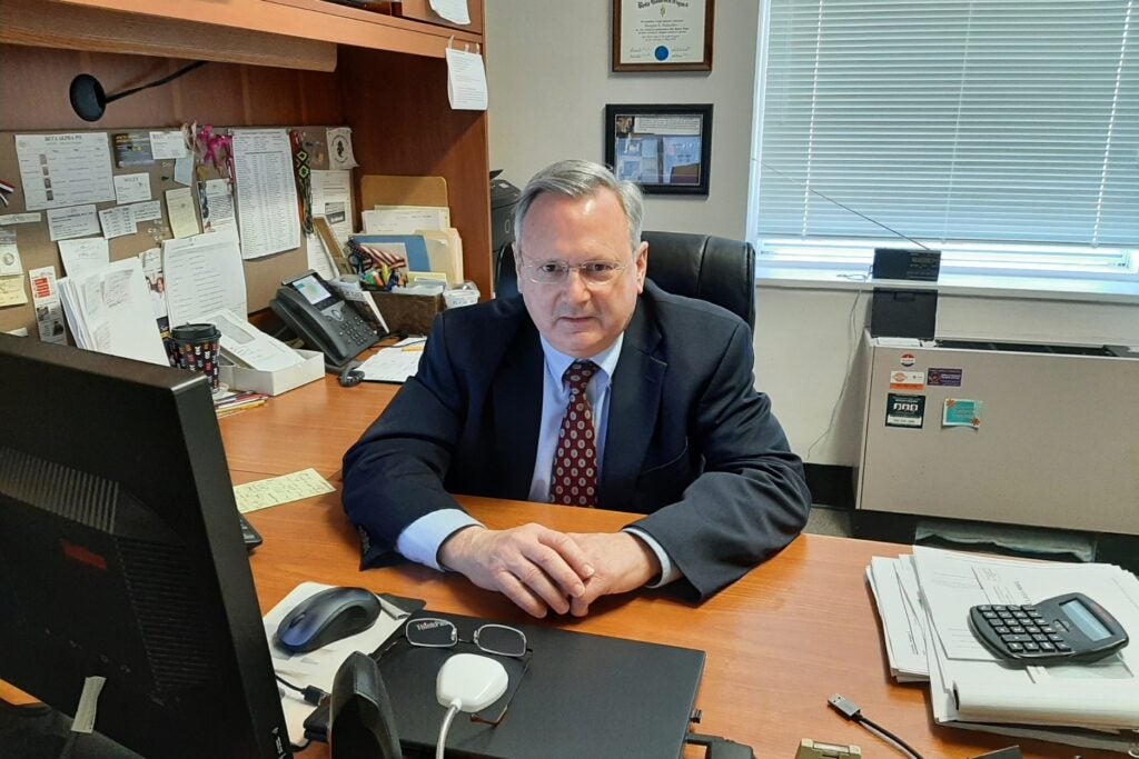 Doug Schneider sits as his desk.