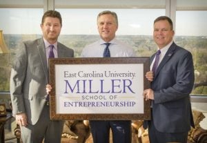 Three men in suits holding a sign reading East Carolina University Miller School of Entrepreneurship